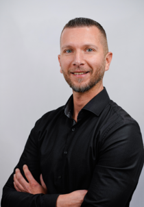 Porträtfoto eines männlichen Teammitglieds mit dunklem Hemd.